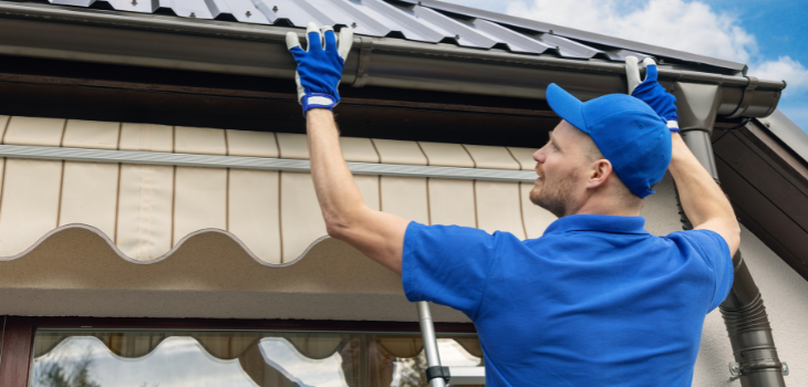 A man installs storm gutters on a house to prepare it for hurricane season.