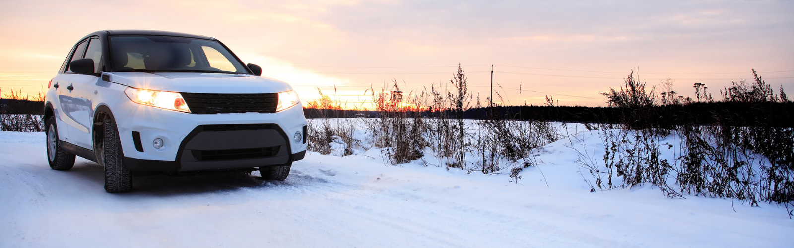 A white car driving down a snowy road.