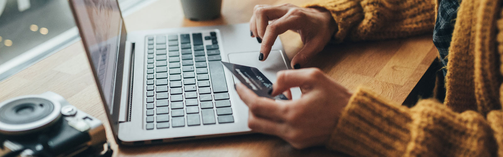 Woman holding card and using laptop.