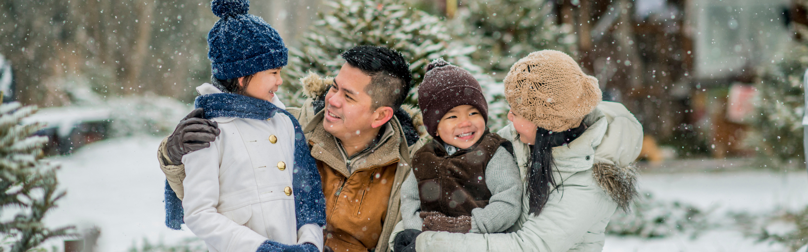 A family four excitedly hold each other while enjoying the snow.
